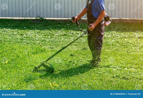 Employee Mows Green Grass On The Lawn With Portable Lawn Mower Stock