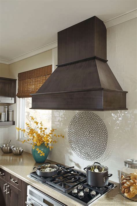The stainless steel strapping and trim give a bit of contrast and depth to the range hood's design. Metal Range Hood - Kitchen Craft Cabinetry