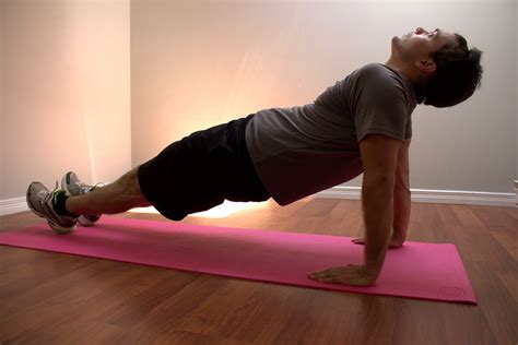 A Man Is Doing Push Ups On A Pink Mat In The Middle Of A Room