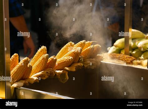 Raw Corn On Cobs And Fire Roasted Corns Displayed Together On A Street