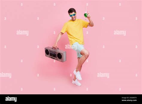 Full Size Photo Of Cheerful Young Happy Man Hold Hands Boombox Drink