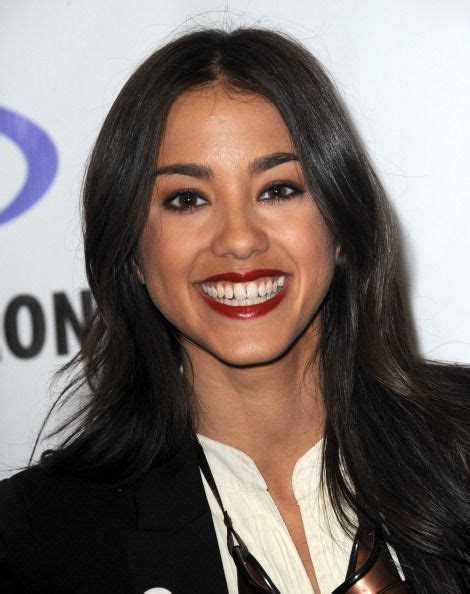 A Woman With Long Dark Hair Smiles At The Camera While Wearing A Black Suit And White Shirt