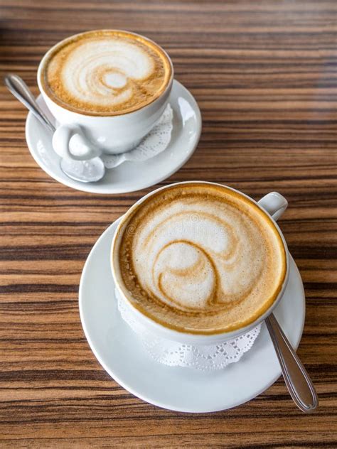 Two Cups Of Cappuccino With Latte Art On Wooden Table Beautiful Foam