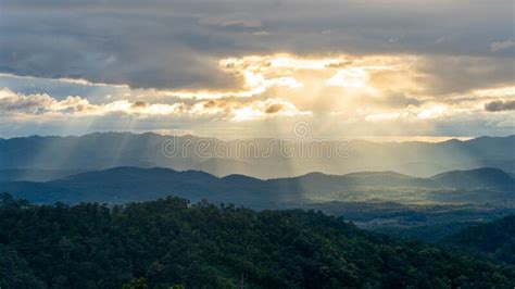 Golden Sun Ray Through Cloudy Sky With Long Mountain Range Stock Image