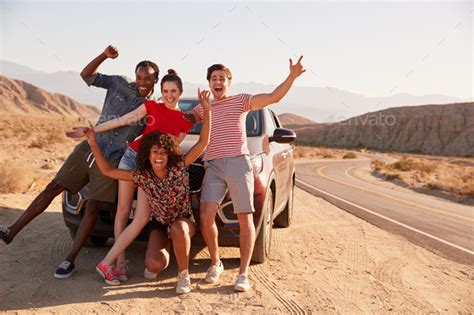 Young Adult Friends On Road Trip Have Fun Posing By The Car Stock Photo