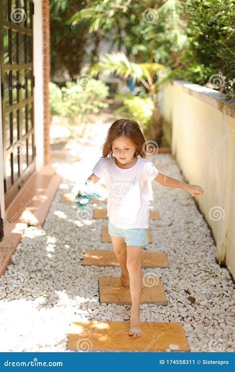 Little Female Kid Walking Barefoot On Gravel Near Hotel Stock Image