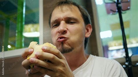 Guy Greedily Eating A Hamburger In A Fast Food Restaurant Stock ビデオ