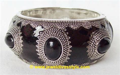 A Black And Silver Bracelet With Two Oval Beads On It S Sides Sitting On A White Surface