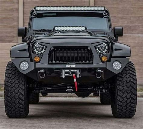The Front End Of A Black Jeep With Lights On