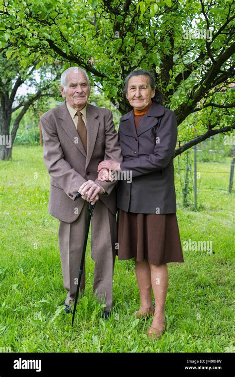 cute 80 plus year old married couple posing for a portrait in their garden love forever concept
