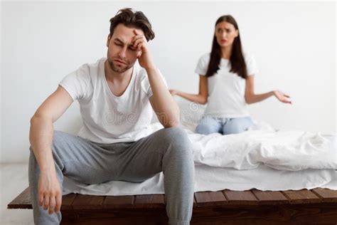 Married Couple Having Quarrel Sitting In Bedroom At Home Stock Image