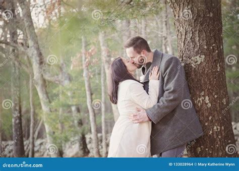 Romantic Young Couple Kissing Under A Tree On A Cold Fall Day Stock