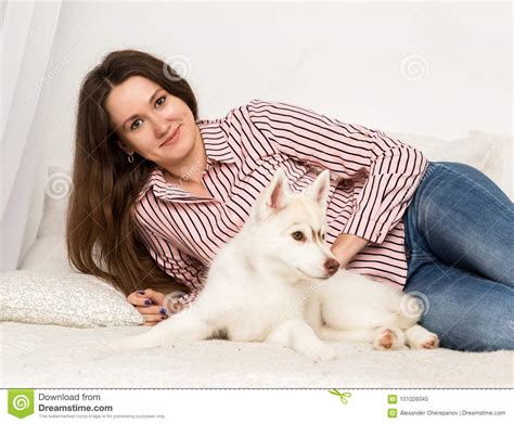 Happy Beautiful Woman Resting On A Couch With Her Pet Girl Hugging