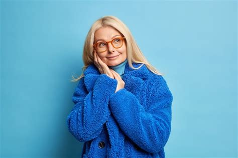 Mujer Rubia De Mediana Edad En Gafas Recuerda Algo Agradable Mantiene Las Manos Cerca De La Cara