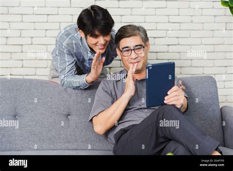 Father Man And His Son Sit On Sofa Talking Chatting On Video Call Stock