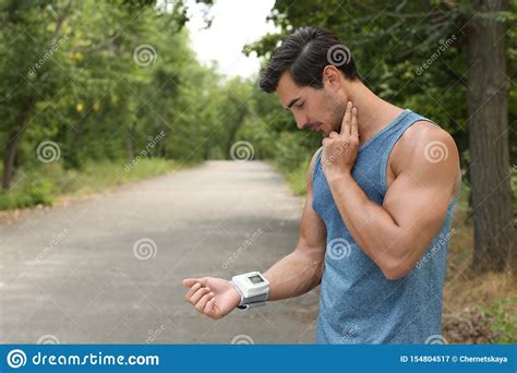 Young Man Checking Pulse With Medical Device After Training In Park