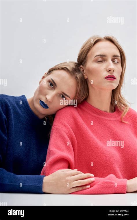 Woman With Blue Lipstick Leaning On Shoulder Of Twin Sister Against