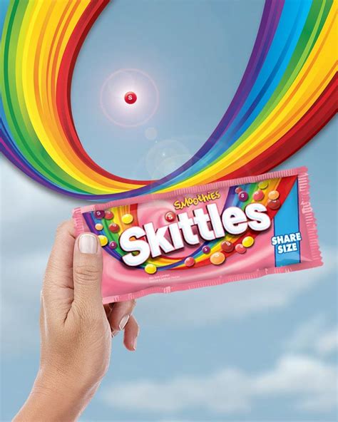 someone holding up a skittles candy bar in front of the sky