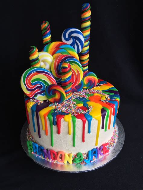 Rainbow Drip Cake With Sprinkles And Lollipops On White Buttercream