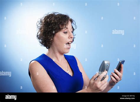 Woman With A Shocked Expression Looking At 2 Phones Stock Photo Alamy