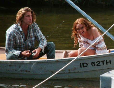 A Man And Woman Sitting In A Small Boat On The Water Smiling At Each Other