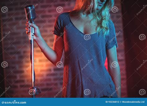 Female Singer With Microphone Standing In Nightclub Editorial