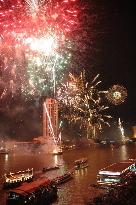 Fireworks Bursting In The Sky Near Buildings By The Body Of Water With