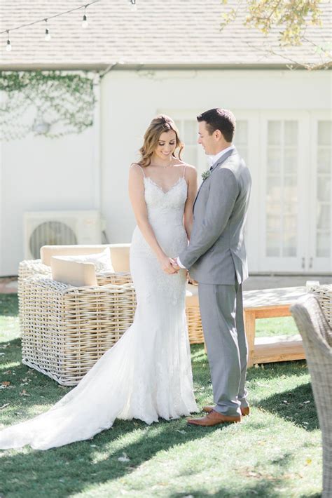 a bride and groom standing in front of a wicker bench at their backyard wedding