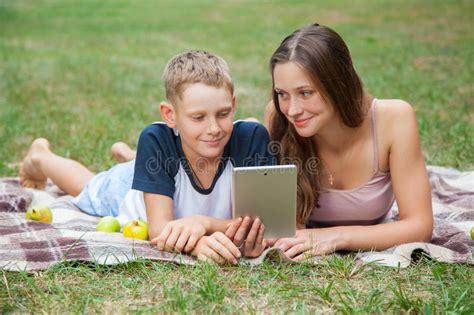 Young Sister And Brother Lying Down And Work With Tablet Stock Image