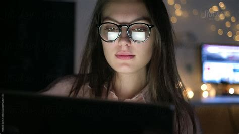 woman in glasses looking on the monitor and working with charts by stocksy contributor nikita