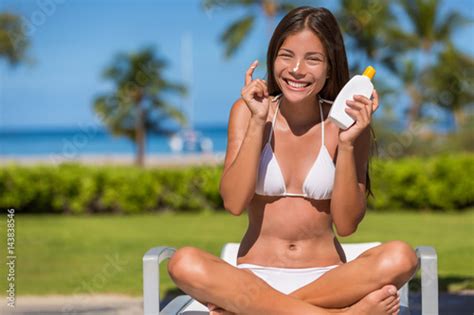 Happy Cute Asian Girl Putting Sunscreen Lotion On Body Showing Suntan Bottle In Summer Resort At