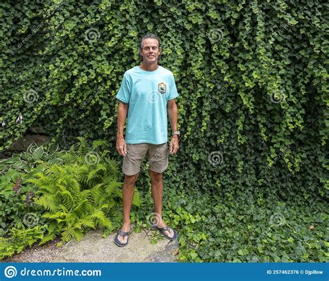 52 year old caucasian male posing in front of a dense wall of green ivy in bar harbor maine