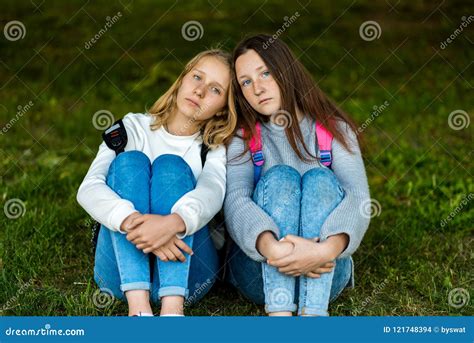 Two Girls Schoolgirl Sitting In The Summer On Grass In The Park Emotions Of Sadness And Sadness