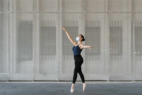 Female Ballet Dancer Standing On Tiptoe While Practicing Against Metal