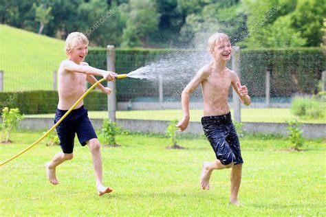 Two Happy Boys Playing In The Garden With Watering Hose Stock Photo By
