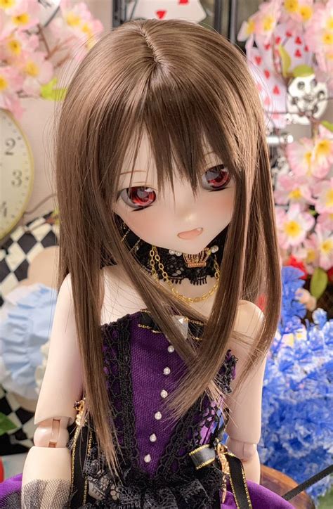 A Close Up Of A Doll With Long Hair Wearing A Dress And Holding A Purse
