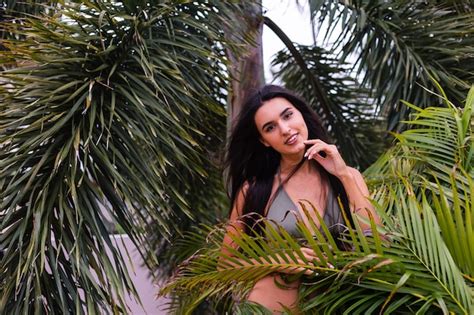 free photo portrait of fit tanned slim woman in green tiny bikini posing with tropical leaves