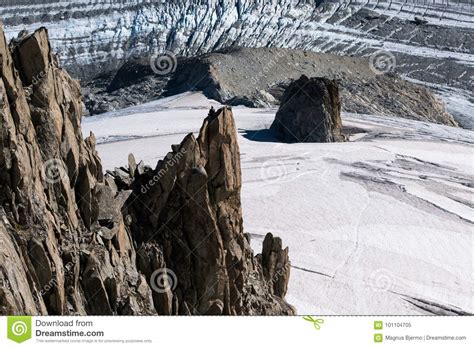 Lone Rock Climber On Top Of Pinnacle Overlooking Glacier Stock Image