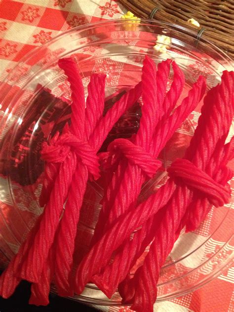 Several Red Ropes Are In A Glass Bowl On A Checkered Tablecloth Covered