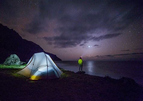 Man Standing Near Body Of Water Near Lighted Dome Tent At Night Night