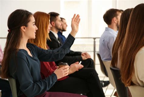 Young Woman Raising Hand To Ask Question At Business Training Stock