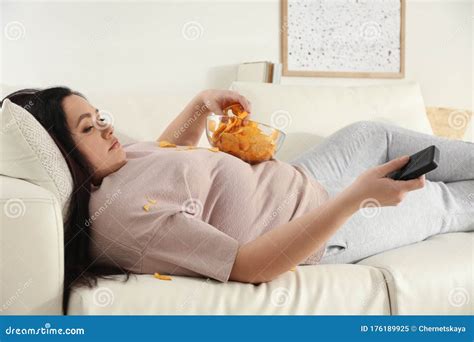 Lazy Overweight Woman With Chips Watching Tv On Sofa Stock Image