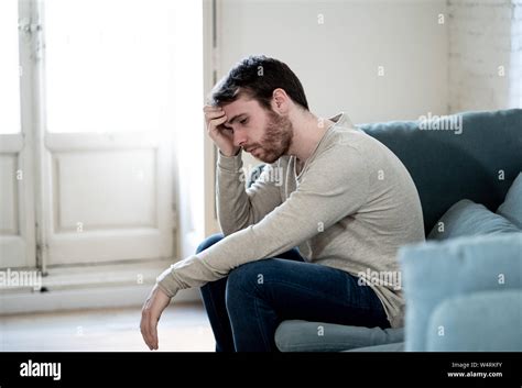 Unhappy Depressed Caucasian Male Sitting And Lying In Living Room Couch