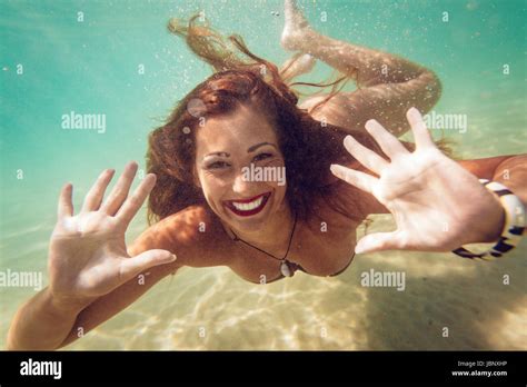 Beautiful Young Woman Diving Underwater In The Sea Looking At Camera