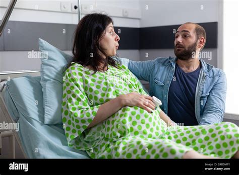 Pregnant Woman Going Into Labor In Hospital Ward Husband Standing Beside Her Comforting