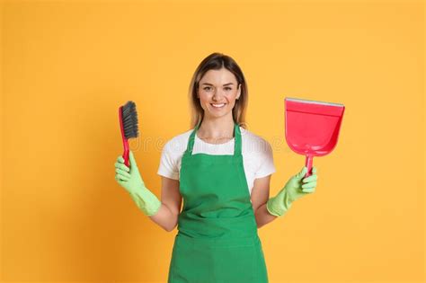 Young Woman With Broom And Dustpan On Orange Background Stock Image