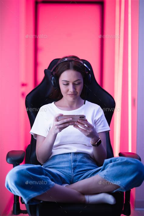 Cybersport Gamer Playing Mobile Game On The Smart Phone Sitting On A Gaming Chair In Neon Color