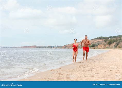 Professional Lifeguards Running At Sandy Beach On Sunny Day Stock Image