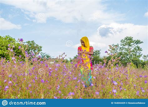 Pretty Young Black Woman Standing In A Field With Purple Flowers Stock
