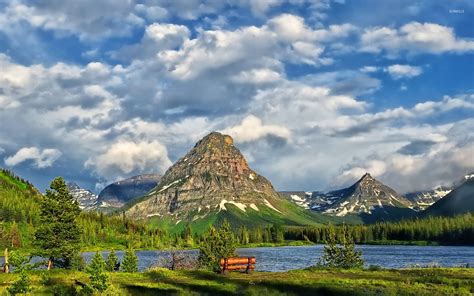 Peaks Rising Towards The Clouds In Glacier National Park Wallpaper